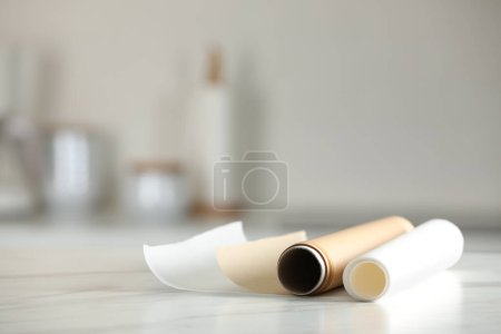 Téléchargez les photos : Rouleaux de papier cuisson sur table en marbre blanc sur fond flou à l'intérieur. Espace pour le texte - en image libre de droit
