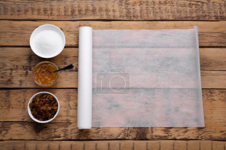 Téléchargez les photos : Rouleau de papier sulfurisé de cuisson avec différents ingrédients sur une table en bois, pose plate. Espace pour le texte - en image libre de droit