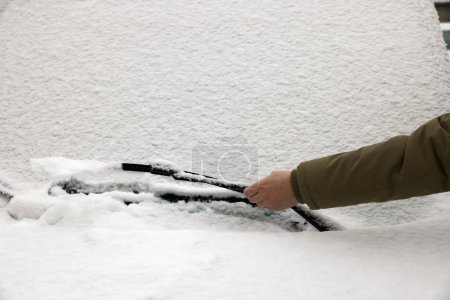 Frau reinigt mit Schnee bedecktes Scheibenwischerblatt
