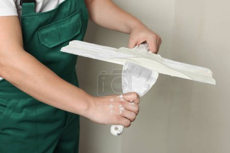 Photo for Professional worker holding putty knives with plaster indoors, closeup - Royalty Free Image