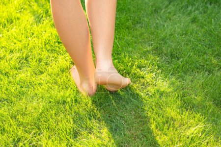 Foto de Adolescente caminando descalzo sobre hierba verde al aire libre, primer plano - Imagen libre de derechos