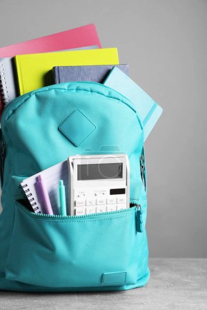 Photo for Turquoise backpack and different school stationery on table against grey background - Royalty Free Image