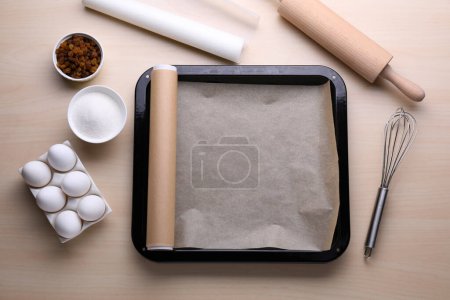 Téléchargez les photos : Plaque de cuisson avec papier sulfurisé, différents ingrédients et outils de cuisine sur table en bois, pose plate - en image libre de droit