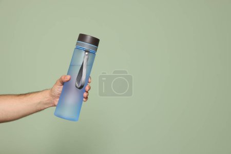 Téléchargez les photos : Homme tenant bouteille d'eau en plastique transparent sur fond vert clair, gros plan. Espace pour le texte - en image libre de droit