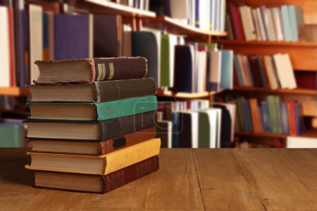Téléchargez les photos : De nombreux livres à couverture rigide empilés sur table en bois dans la bibliothèque, espace pour le texte - en image libre de droit