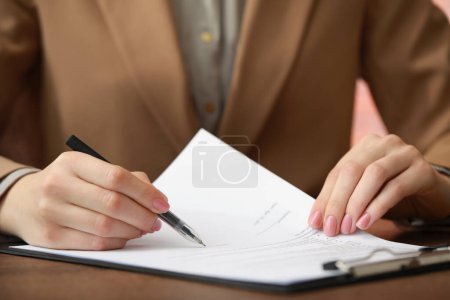 Foto de Mujer firmando documentos en la mesa de madera en la oficina, primer plano - Imagen libre de derechos