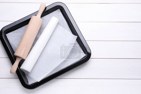 Téléchargez les photos : Plaque de cuisson avec papier sulfurisé et rouleau à pâtisserie sur table en bois blanc, vue sur le dessus. Espace pour le texte - en image libre de droit