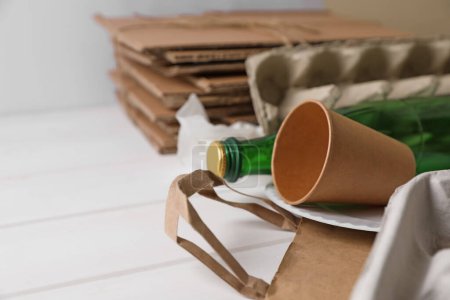 Photo for Heap of waste paper and glass bottle on white wooden table, closeup. Space for text - Royalty Free Image