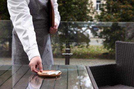 Kellner holt sich Tipps von Holztisch in Outdoor-Café, Nahaufnahme