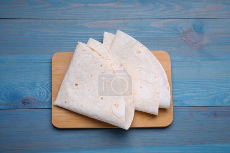 Photo for Delicious folded Armenian lavash on light blue wooden table, top view - Royalty Free Image