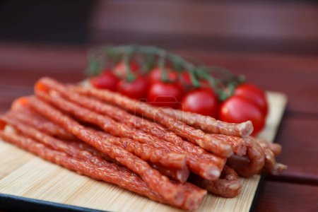 Photo for Tasty dry cured sausages (kabanosy) on wooden table, closeup - Royalty Free Image