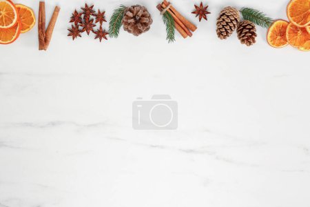 Téléchargez les photos : Tranches d'orange sèches, bâtonnets de cannelle, branches de sapin et étoiles d'anis sur table en marbre blanc, disposition plate avec espace pour le texte - en image libre de droit