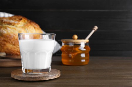 Foto de Vaso con leche fresca, miel y pan sobre mesa de madera. Espacio para texto - Imagen libre de derechos