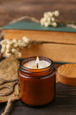 Foto de Burning scented candle, book and flowers on wooden table - Imagen libre de derechos