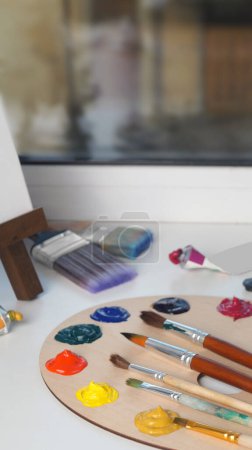 Foto de Artist's palette with samples of colorful paints and brushes on white table - Imagen libre de derechos