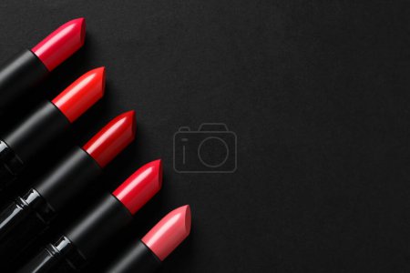 Photo for Beautiful lipsticks on black background, flat lay. Space for text - Royalty Free Image