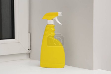 Téléchargez les photos : Yellow spray bottle of cleaning product on window sill indoors - en image libre de droit