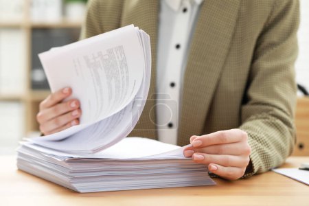 Mujer trabajando con documentos en la mesa en la oficina, primer plano
