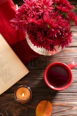 Photo for Beautiful chrysanthemum flowers, cup of tea and book on wooden table indoors, flat lay - Royalty Free Image
