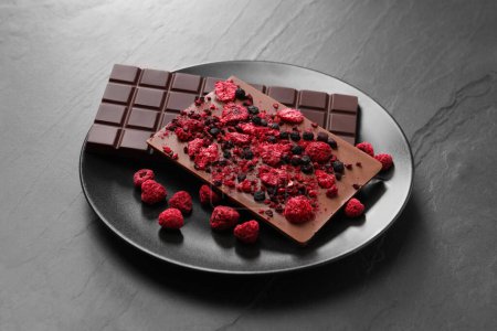 Photo for Plate and different chocolate bars with freeze dried fruits on slate table - Royalty Free Image