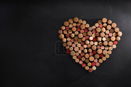 Photo for Heart made of wine bottle corks on black table, top view. Space for text - Royalty Free Image