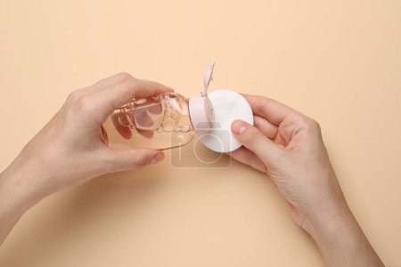 Photo for Woman pouring micellar water from bottle onto cotton pad against beige background, closeup - Royalty Free Image