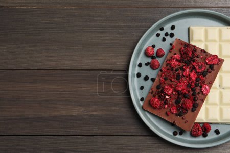 Photo for Plate and different chocolate bars with freeze dried fruits on wooden table, top view. Space for text - Royalty Free Image