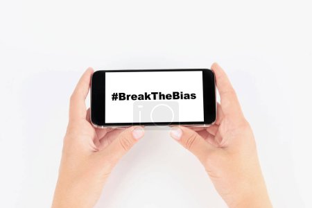 Photo for Woman holding smartphone with hashtag BreakTheBias on screen against white background, closeup. Campaign theme for International Women's Day - Royalty Free Image