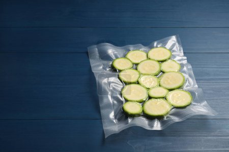 Photo for Plastic bag with cut zucchinis on blue wooden table. Space for text - Royalty Free Image