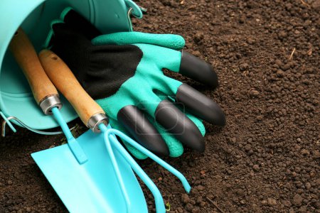 Foto de Overturned bucket with gardening tools and gloves on fresh soil. Space for text - Imagen libre de derechos