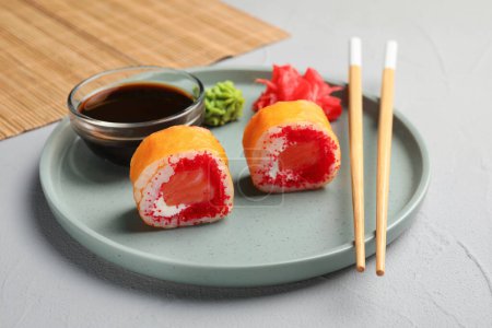 Foto de Deliciosos rollos de sushi, salsa de soja, wasabi, jengibre y palillos en la mesa de textura gris, primer plano - Imagen libre de derechos