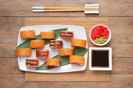 Foto de Composición plana con deliciosos rollos de sushi sobre mesa de madera - Imagen libre de derechos