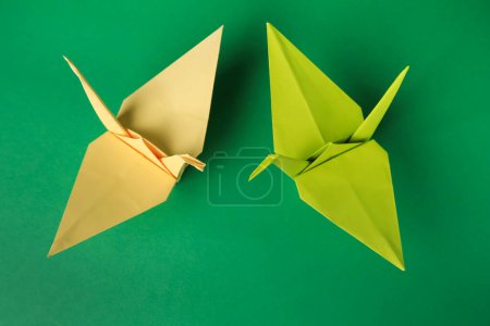 Foto de Colorful paper origami cranes on green background, flat lay - Imagen libre de derechos
