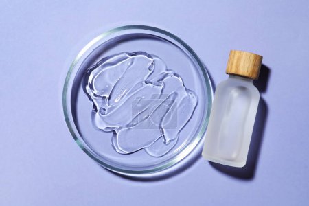 Petri dish with sample and bottle on lilac background, flat lay