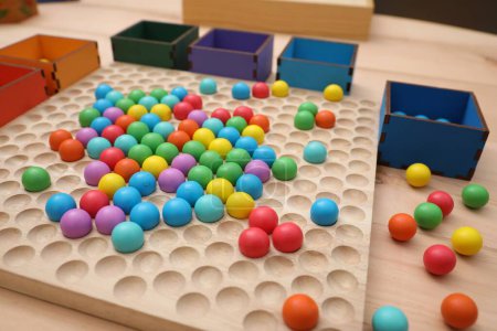 Photo for Wooden sorting board and boxes with colorful balls on table, closeup. Montessori toy - Royalty Free Image