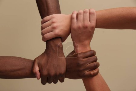 Foto de Hombres uniendo las manos sobre fondo beige, primer plano - Imagen libre de derechos