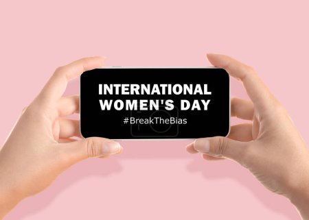 Photo for Woman holding smartphone with hashtag BreakTheBias on screen against pink background, closeup. Campaign theme for International Women's Day - Royalty Free Image