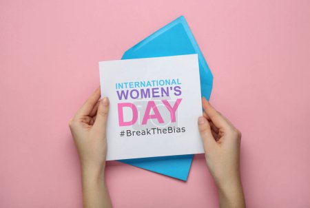 Photo for Woman holding card with phrase International Women's Day and hashtag BreakTheBias on pink background, top view - Royalty Free Image