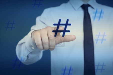 Photo for Hashtag concept. Man pointing at sign on blue background, closeup - Royalty Free Image
