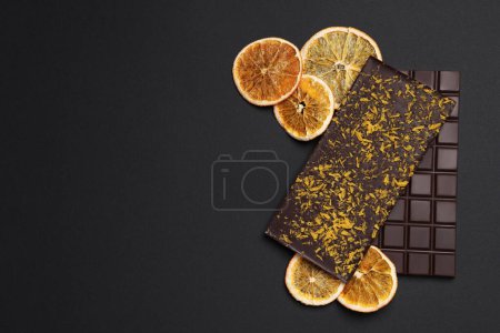 Photo for Chocolate bars with freeze dried orange on black background, flat lay. Space for text - Royalty Free Image