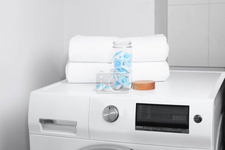 Téléchargez les photos : Pot en verre avec des comprimés d'adoucissant d'eau sur la machine à laver dans la salle de bain - en image libre de droit