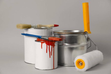 Téléchargez les photos : Cans of orange paint, brushes and roller on grey background - en image libre de droit
