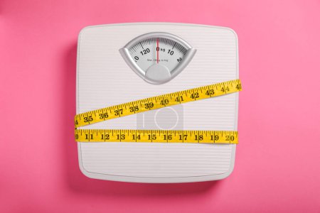 Téléchargez les photos : Weight loss concept. Scales and measuring tape on pink background, top view - en image libre de droit