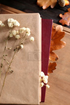 Photo for Stack of book with autumn leaves and flowers as bookmarks on wooden table, flat lay - Royalty Free Image