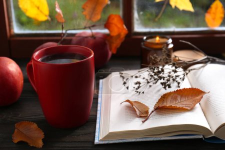 Photo for Book with dried flower as bookmark and cup of hot drink on wooden table - Royalty Free Image