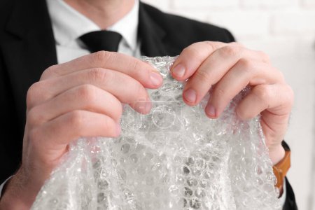 Photo for Businessman popping bubble wrap, closeup view. Stress relief - Royalty Free Image