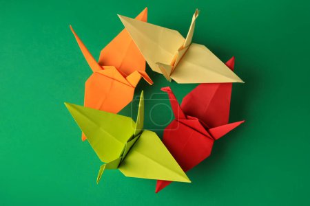 Foto de Colorful paper origami cranes on green background, flat lay - Imagen libre de derechos