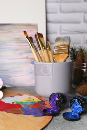 Foto de Artist's palette, tubes of colorful paints and brushes on textured table - Imagen libre de derechos