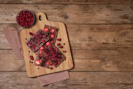 Photo for Chocolate bars with freeze dried fruits on wooden table, flat lay. Space for text - Royalty Free Image