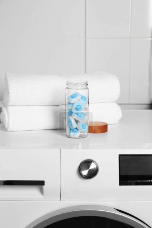 Photo for Glass jar with water softener tablets on washing machine in bathroom - Royalty Free Image